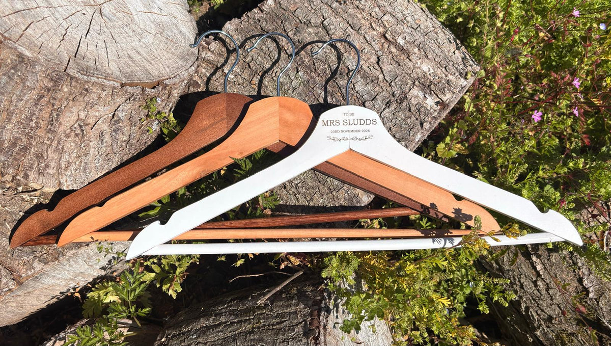 White, light wood and dark wood wedding hangers displayed together on a rustic wooden background.