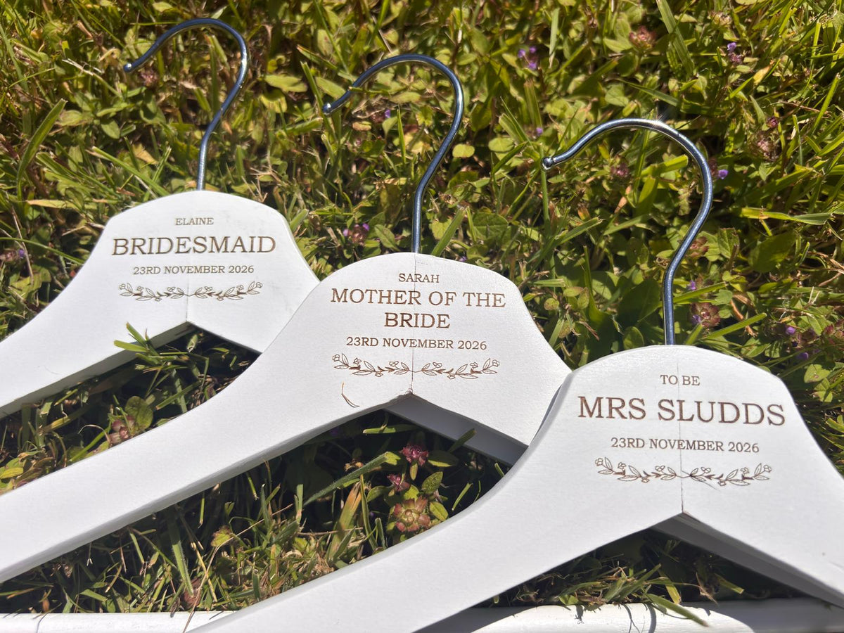 Three white personalised wooden wedding hangers engraved for bride, bridesmaid and mother of the bride.