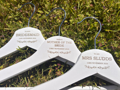 Three white personalised wooden wedding hangers engraved for bride, bridesmaid and mother of the bride.