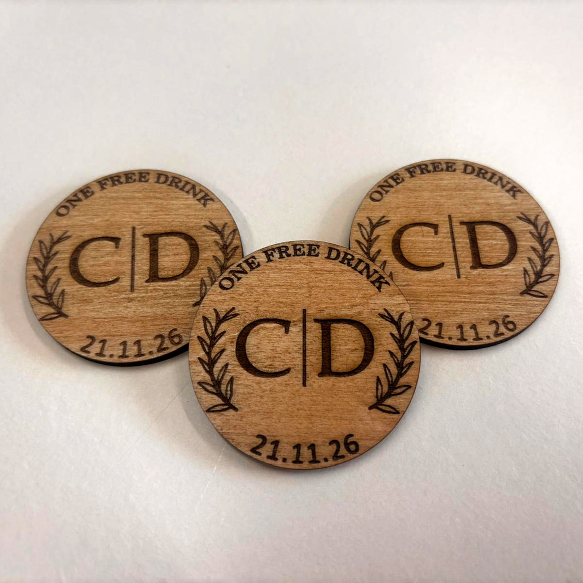 Round wooden wedding drink tokens personalised with couple's initials, wedding date and One Free Drink engraving.